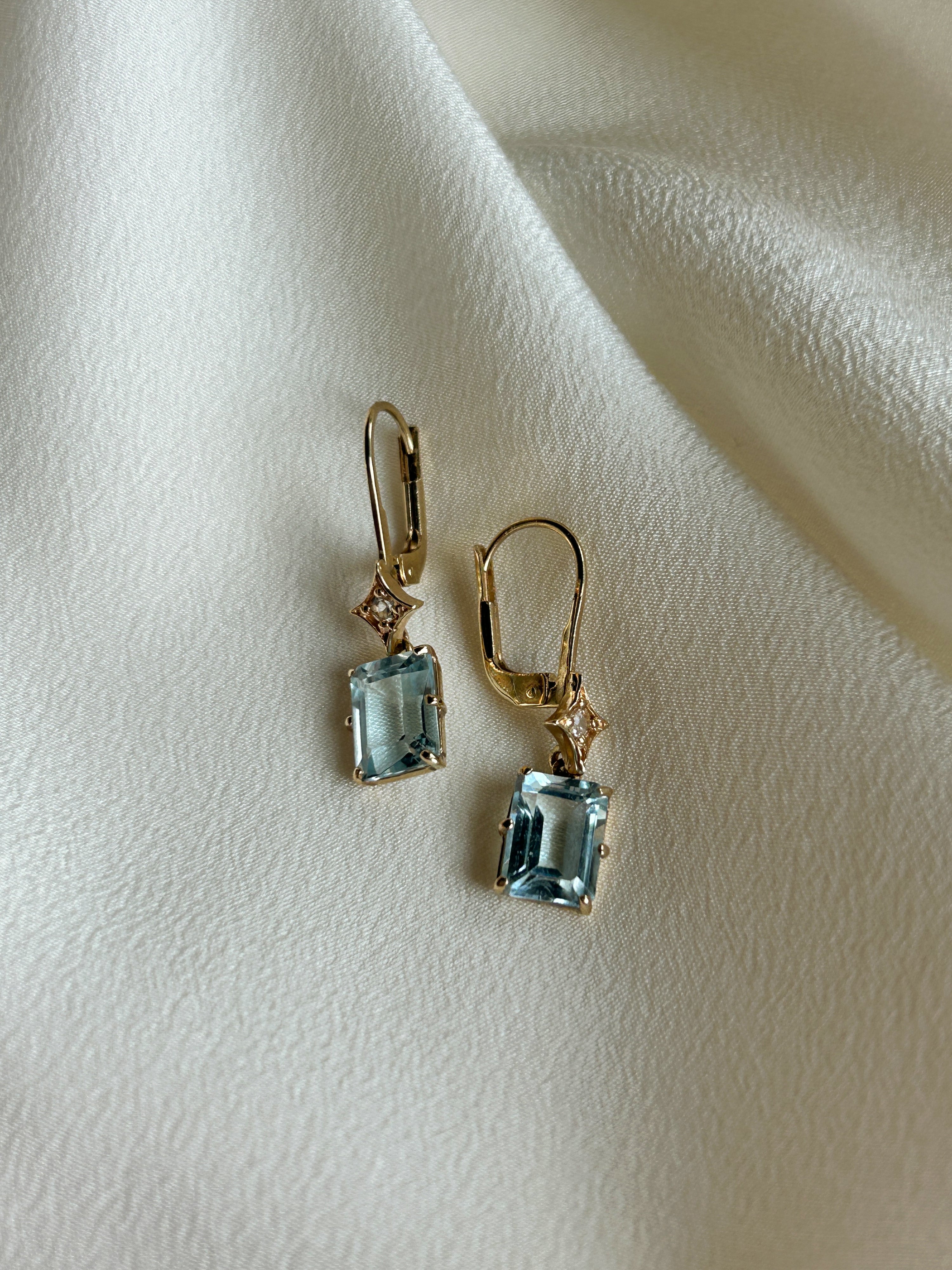 Gold earrings with blue gemstones on a light fabric background